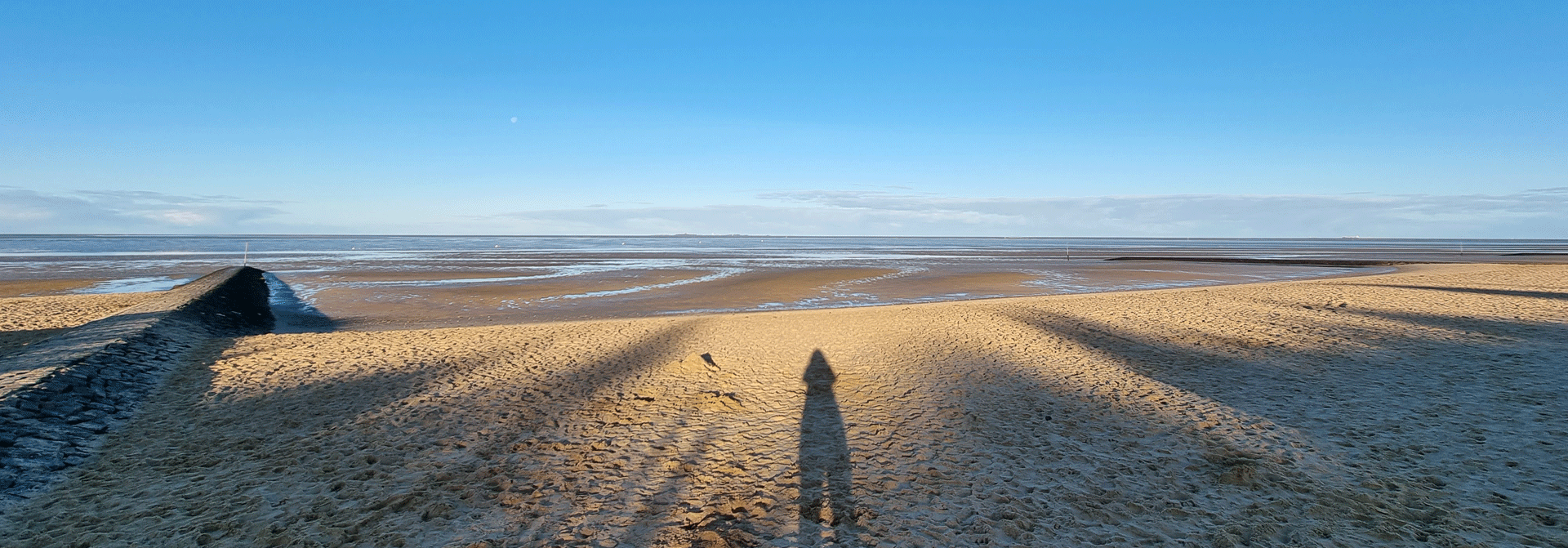 Mensch wirft Schatten im Sonnenuntergang am Strand der Nordsee